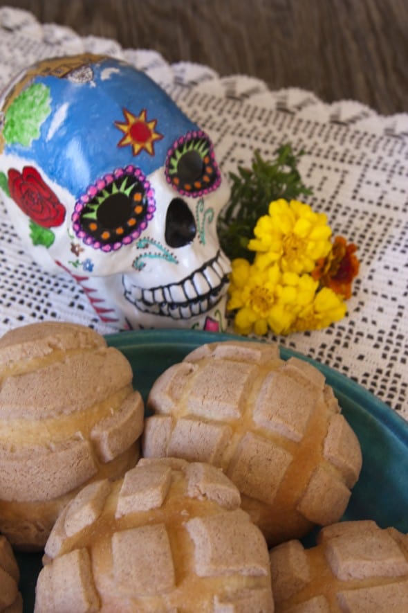 plate of Mexican sweet bread conches with a sugar skull and marigolds