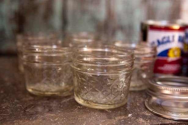 six 4-ounce glass jars with lids and bands with a can of Eagle brand milk in background.