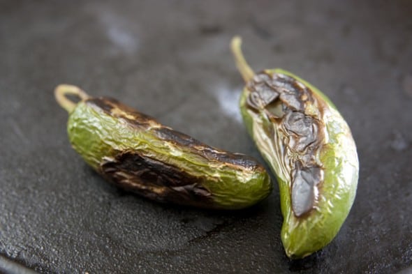 two jalapeños roasted on a black background 