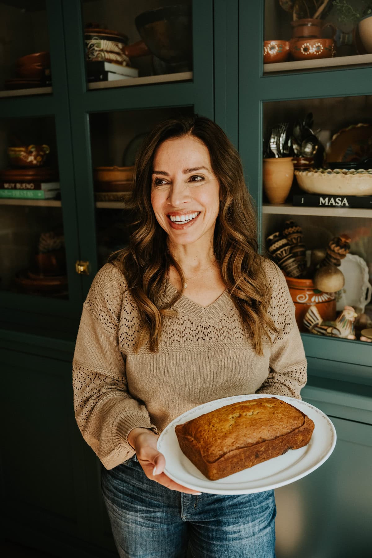 Yvette Marquez holding a loaf of freshly baked Mexican pumpkin bread in her kitchen.