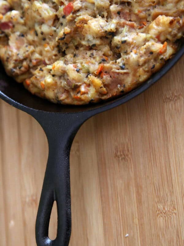 a black cast iron skillet with homemade Thanksgiving stuffing on a wooden table.