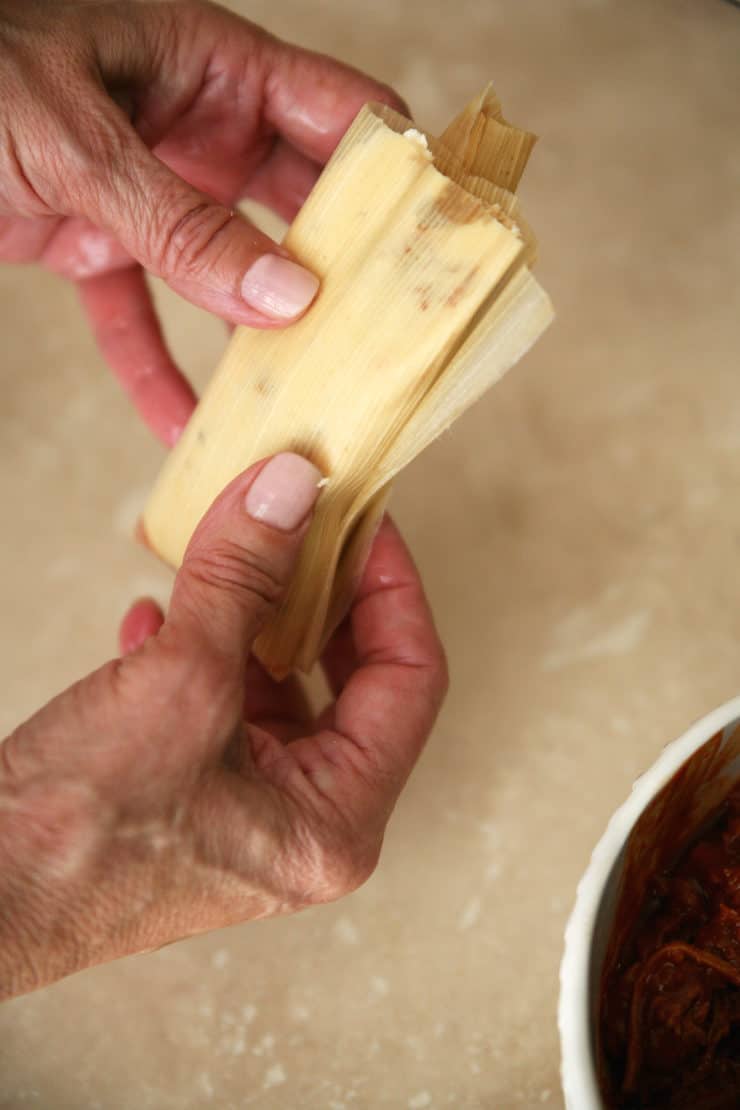 Tamal Dough (Masa para Tamales) hands holding a raw tamal