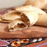 halved persimmon empanada on a wooden cutting board
