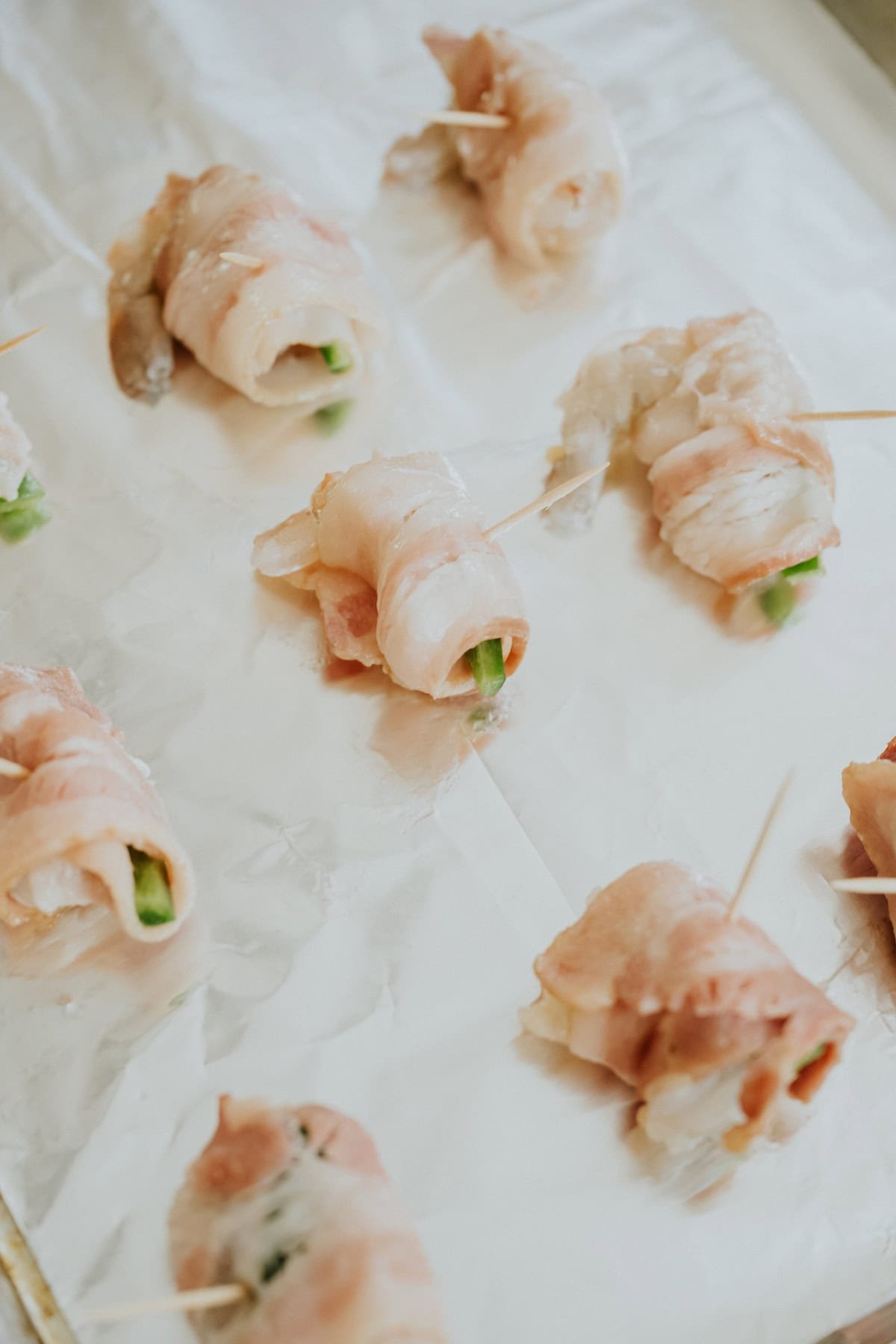 Uncooked shrimp stuffed with jalapeño and wrapped in bacon secured with toothpicks.