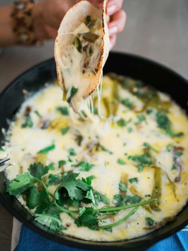 hand holding tortilla filled with queso fundido with hatch chiles and mushrooms