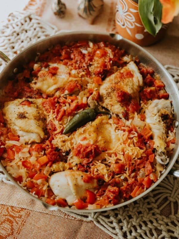 Skillet filled with golden chicken pieces and rice simmered in tomatoes and broth.