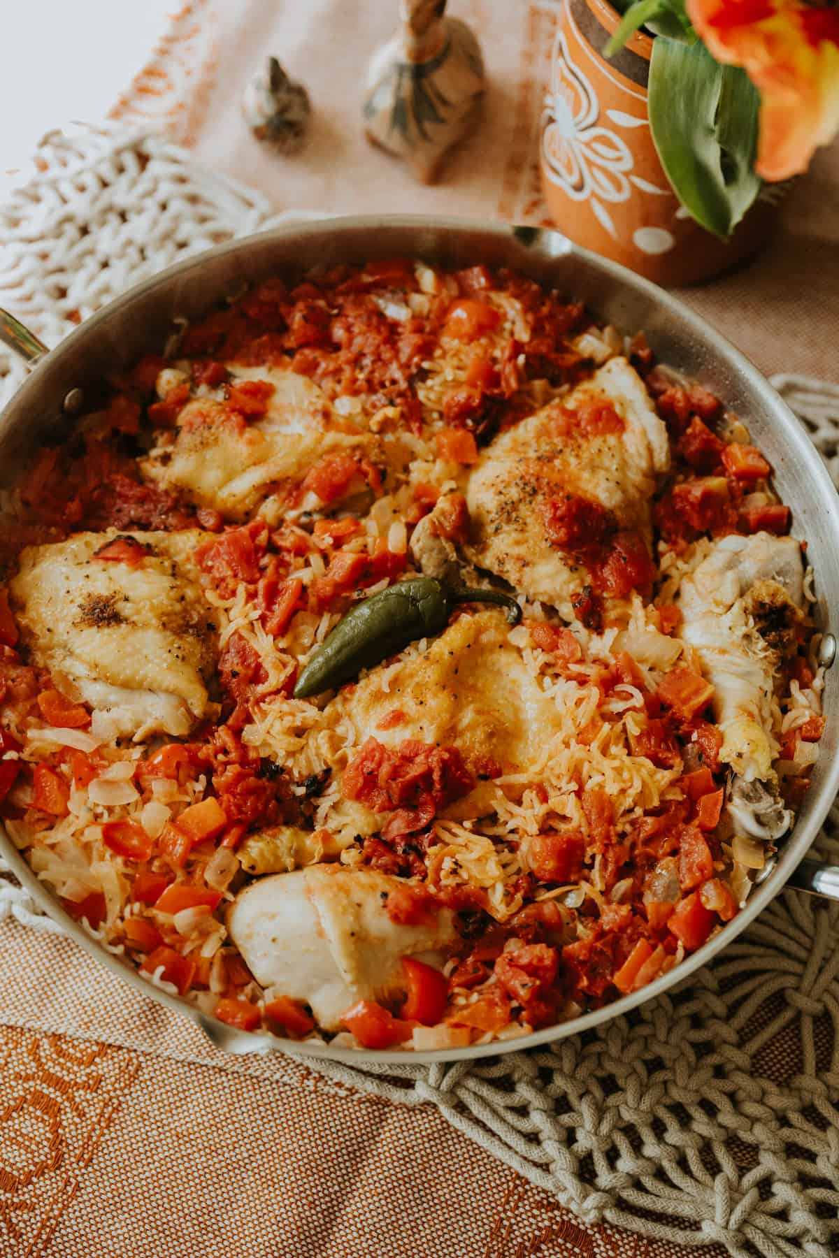 One-pan Arroz con Pollo cooking on the stove with chicken, rice, and a jalapeño on top.
