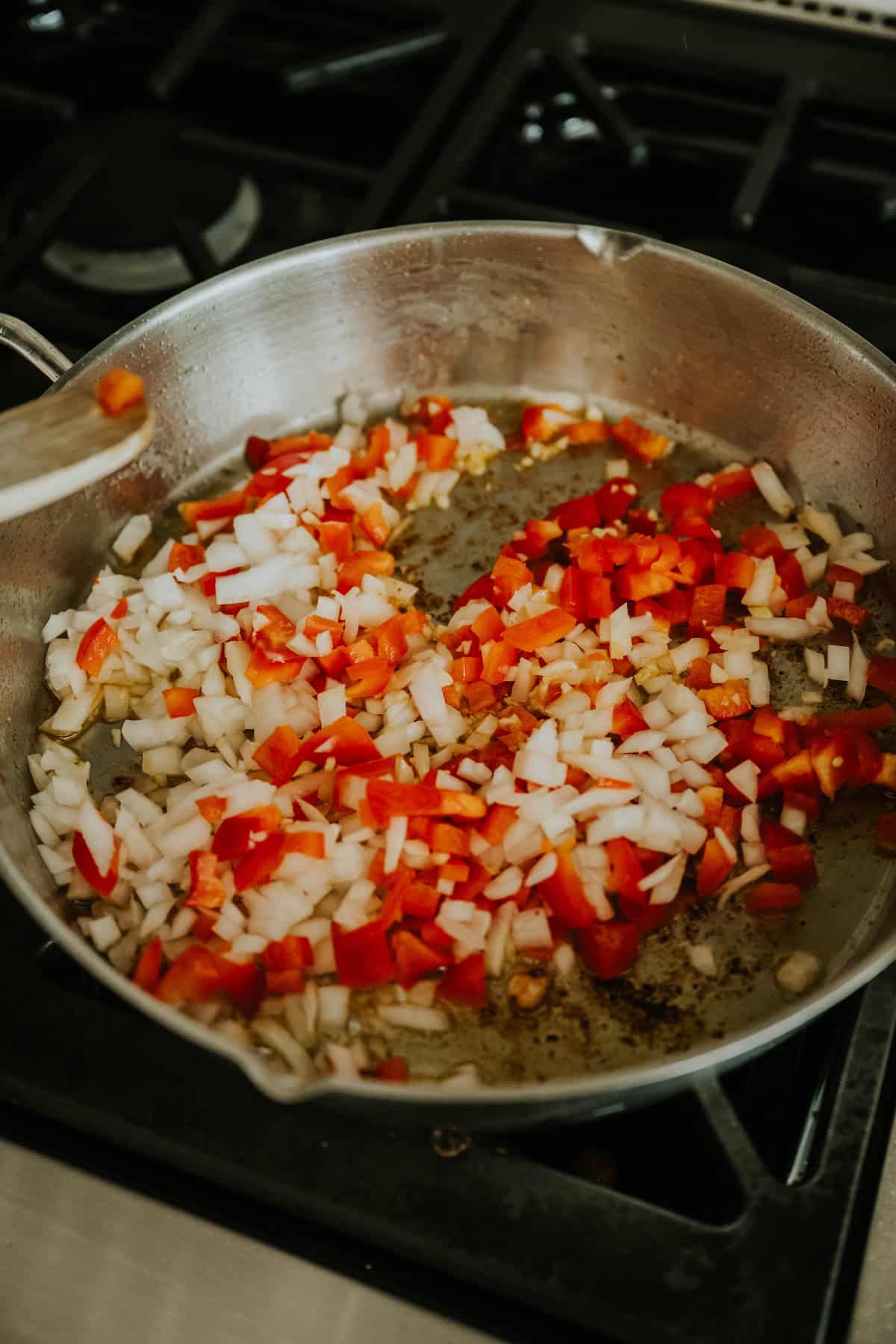 Chopped onions and bell peppers sautéing in a skillet for Arroz con Pollo.