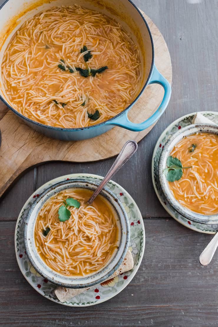 turquoise enameled pot filled with sopa de fideo and two bowls filled with the soup to the side