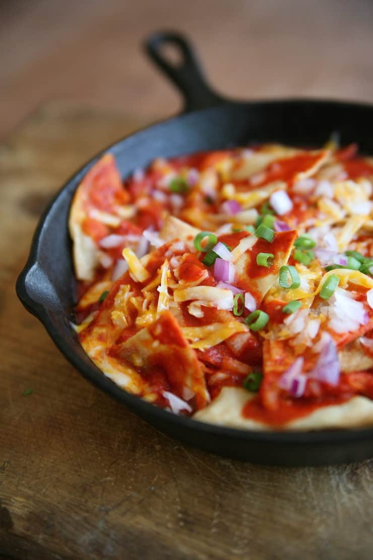chilaquiles rojas in a cast iron pan on a wooden cutting board