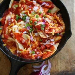 chilaquiles rojos in cast iron pan on a wooden cutting board
