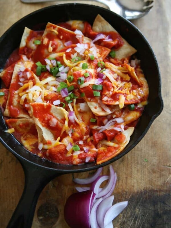 chilaquiles rojos in cast iron pan on a wooden cutting board