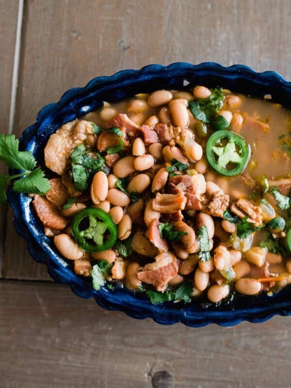 Overhead close-up of bacon-filled borracho beans in a blue serving dish.