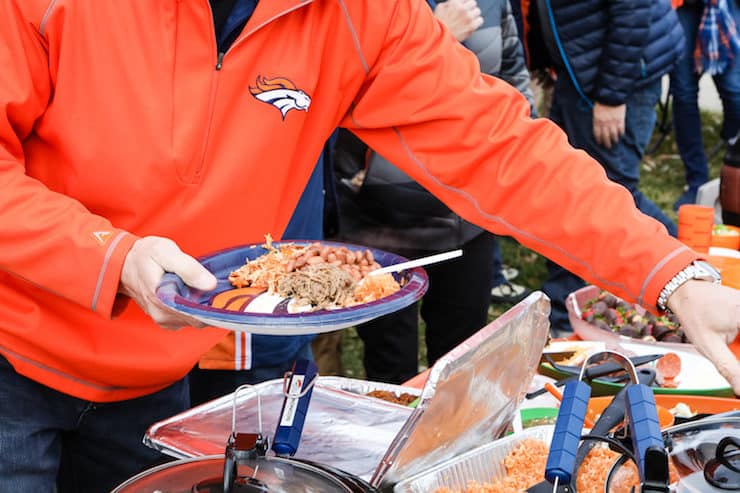 holding a Denver Broncos paper plate with tailgate food 