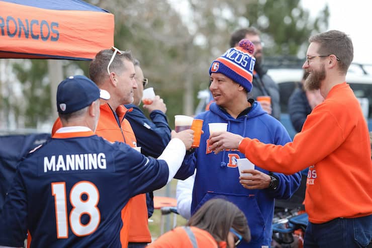 four Denver Broncos fans drinking beer at a tailgate
