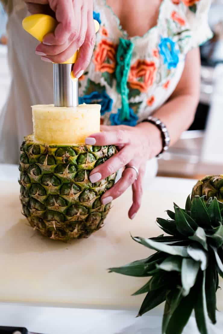 Latina blogger using a pineapple corer to remove fresh pineapple from the skin.