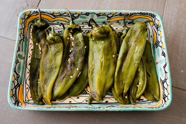 peeled, fire roasted chiles on a painted ceramic tray