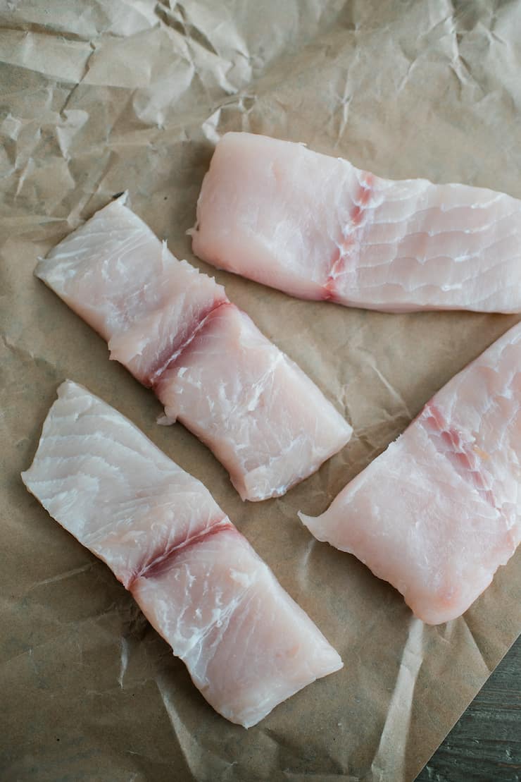 Four pieces of raw tilapia fillets ready for cooking.