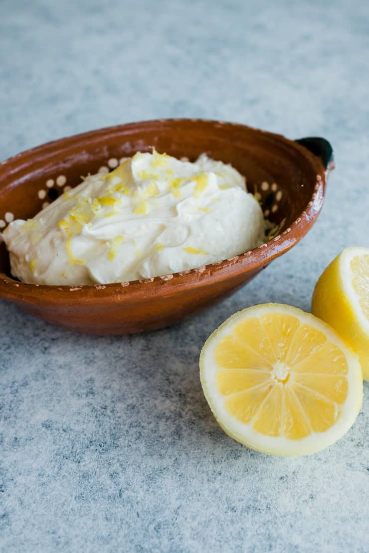 Homemade lemon whipped cream frosting with two halves of lemon