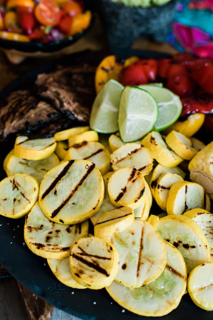 black plate with grilled summer squash, bell peppers and mushrooms