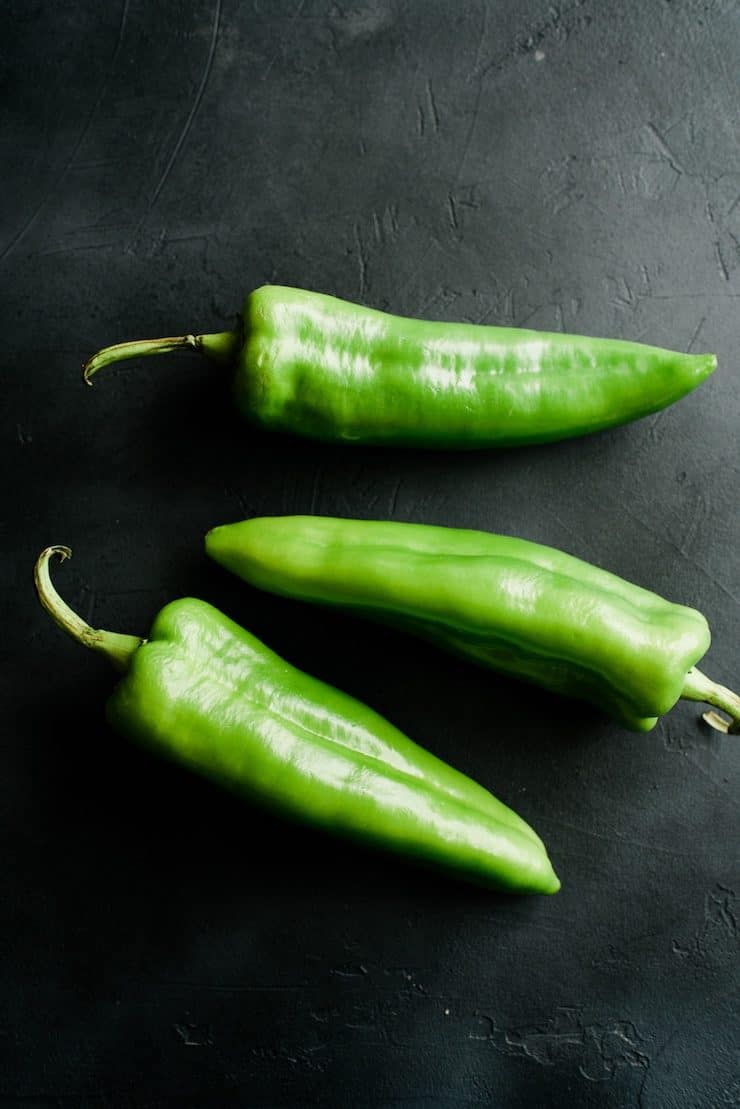 three Anaheim Chile peppers on a black background 