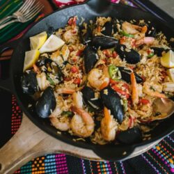 seafood paella de marisco in a cast iron pan on a striped table runner.