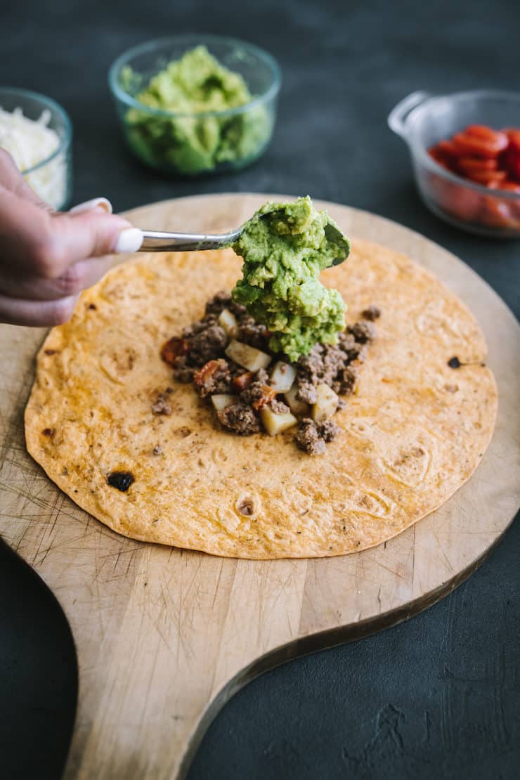 hand dolloping guacamole to make a homemade picadillo Crunchwrap 