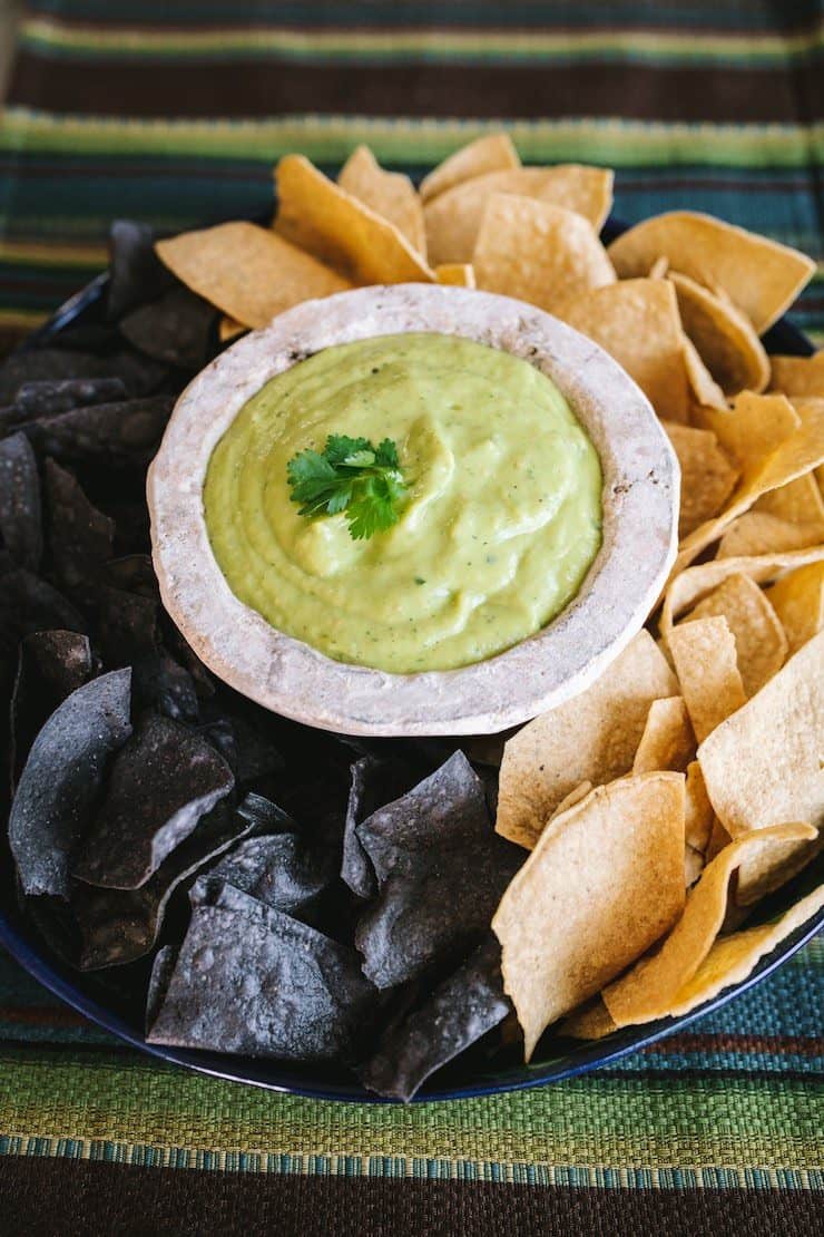 Tomatillo Avocado Salsa in a white molcajete surrounded by tortilla chips