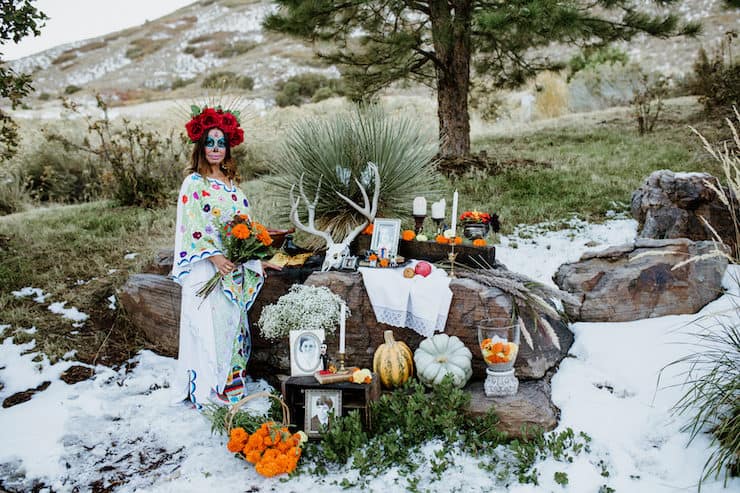 La Calavera Catrina in front of an altar ofrenda with snow on ground