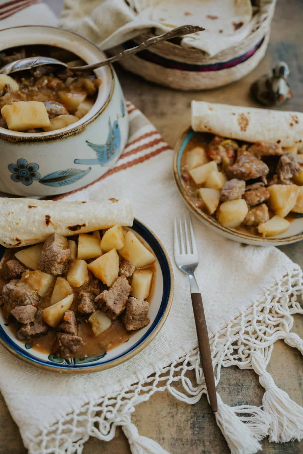 A serving of Chile Verde con Carne y Papas on a plate with warm corn tortillas, showcasing tender beef, potatoes, and green chile stew.