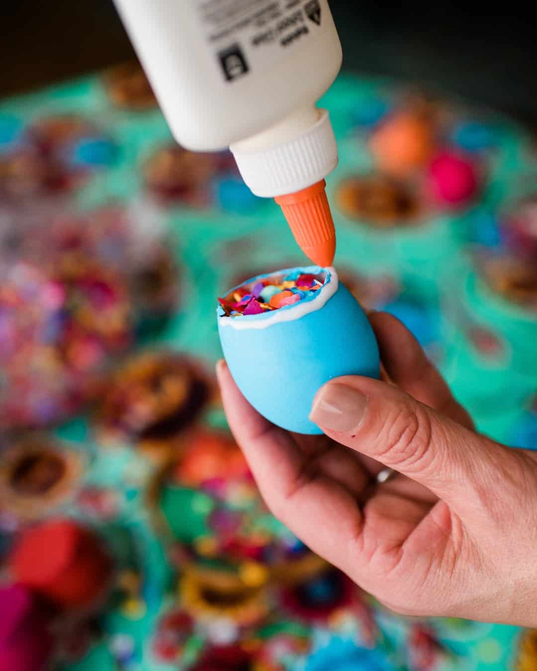 Dyed easter egg shell filled with confetti and being glued on top.