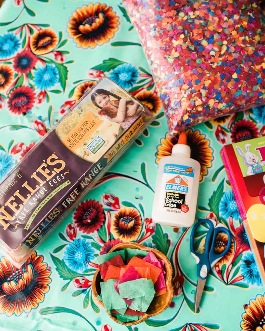 supplies to make cascarones - eggs, scissors tissue paper and glue, and confetti.