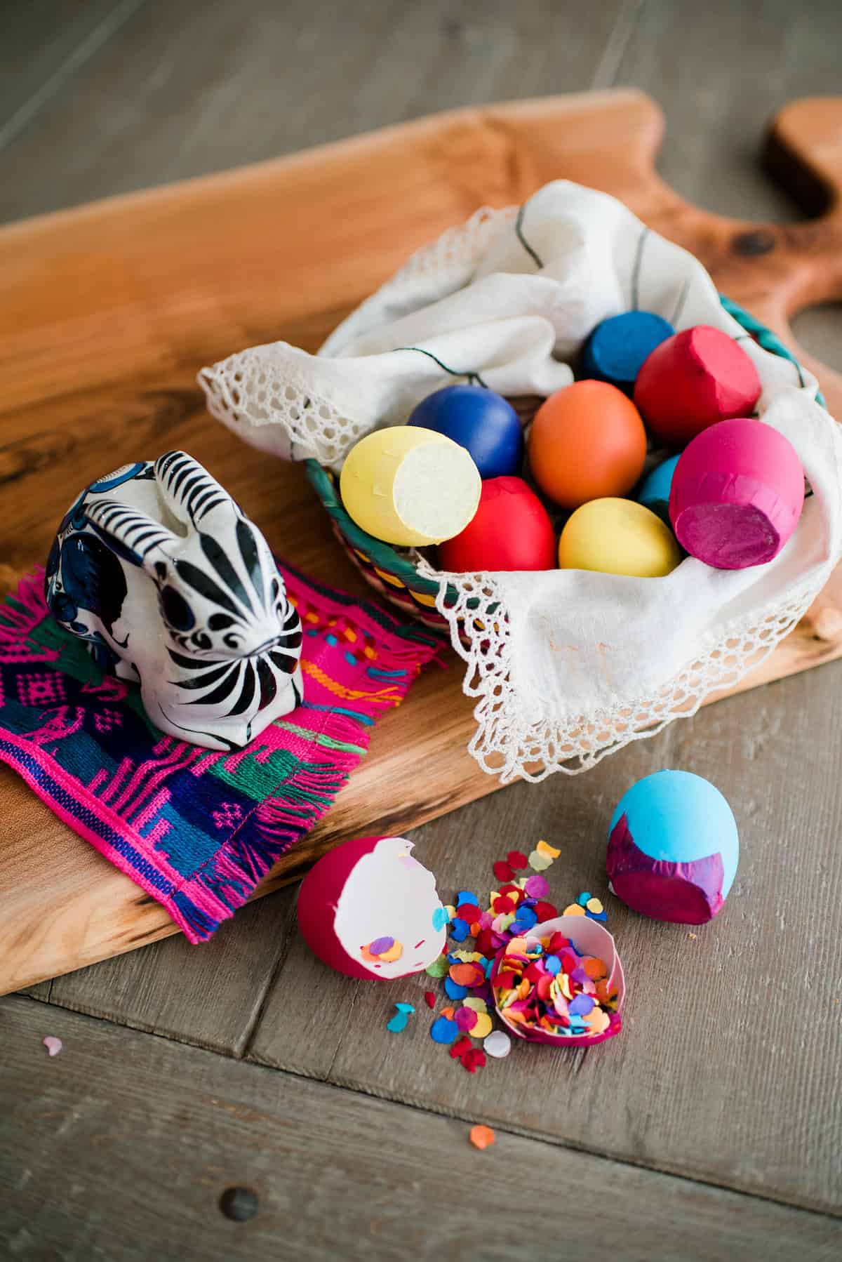 Colorful confetti filled easter eggs called cascarones in a basket near a ceramic Mexican painted rabbit.