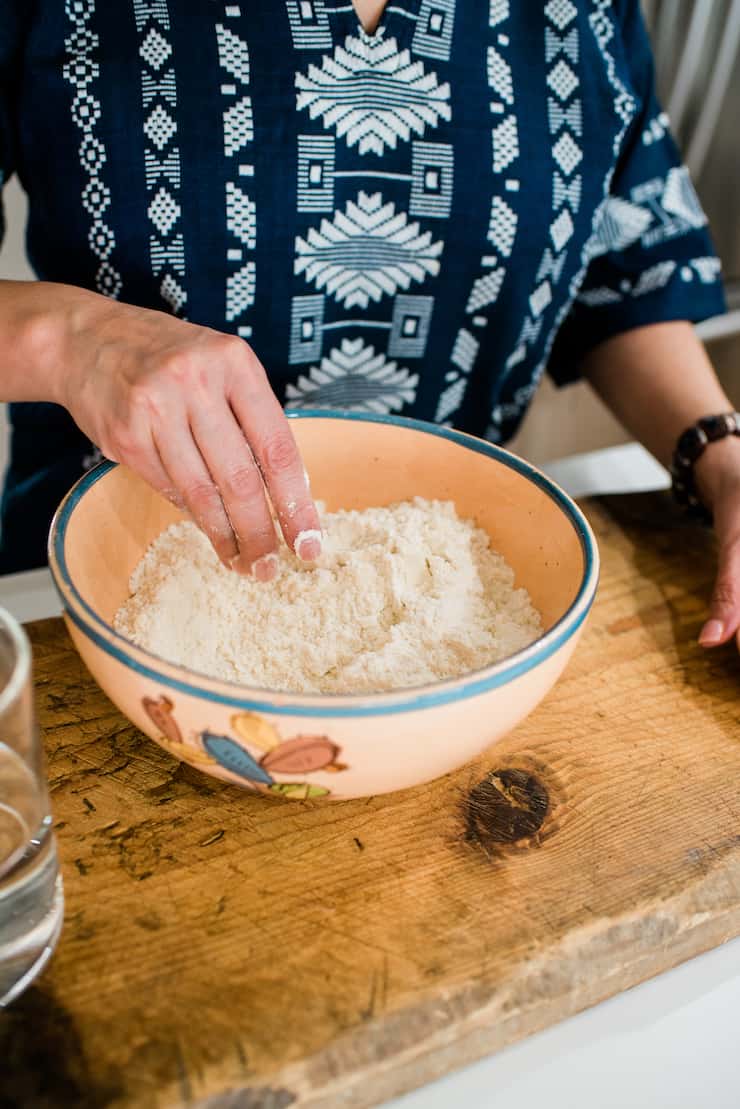 Corn flour masa harina in a Mexican vinage bowl and woman hands in bowl showing texture