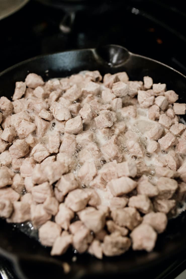 browning pork loin cubes in a cast iron skillet. 