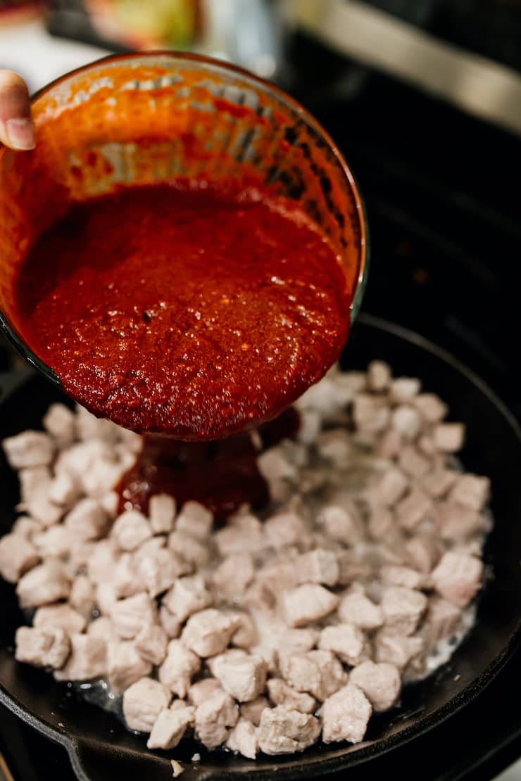 homemade red chile sauce pouring onto pork pieces