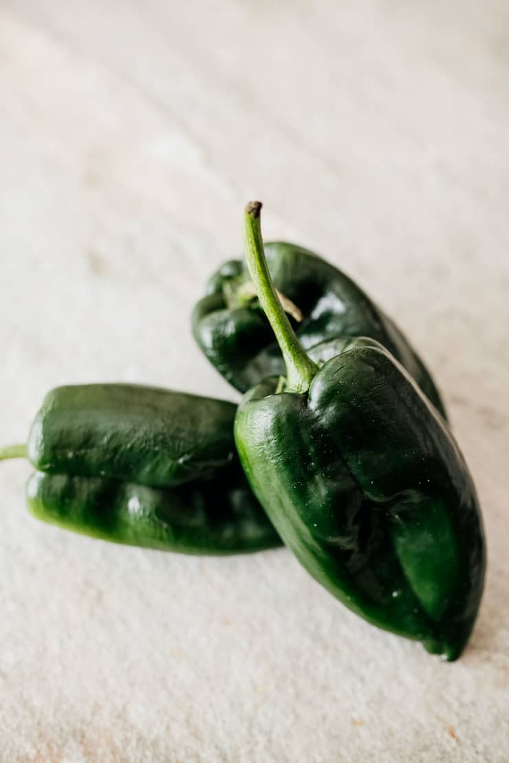 3 poblano peppers on a white surface.