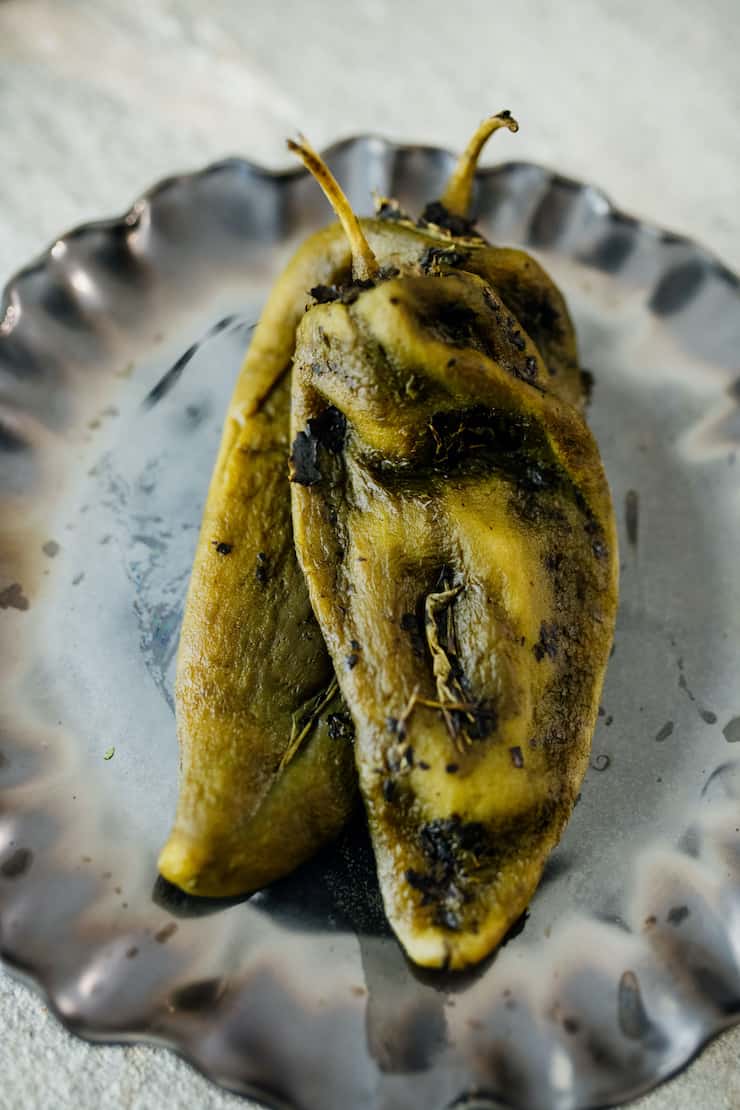 three roasted and peeled poblanos on a white and black plate