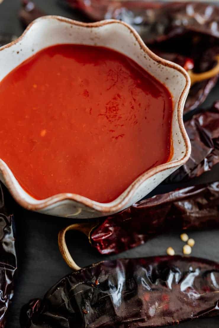 homemade enchilada sauce in a bowl surrounded with dried Chile pods