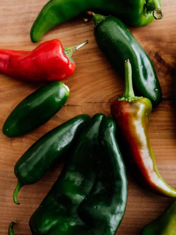 assorted fresh Mexican chiles on a wooden board