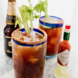 two michelada beer cocktails with hot sauce and Mexican beer