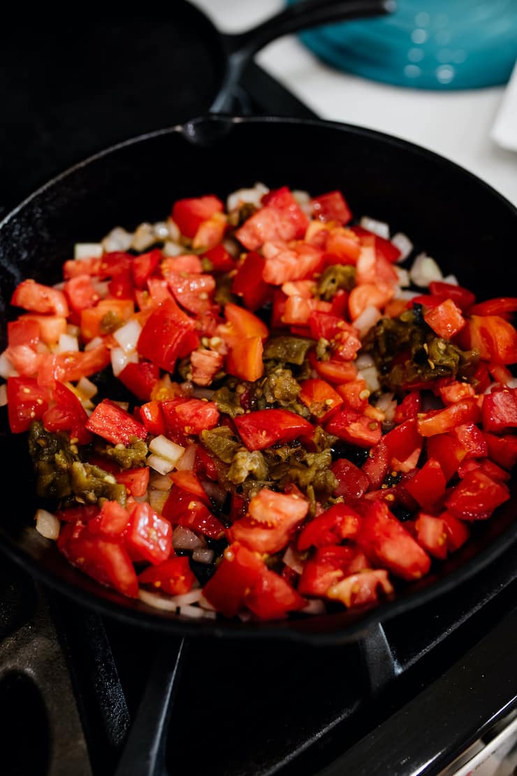 diced onions, tomatoes and roasted green chiles in a cast iron skillet