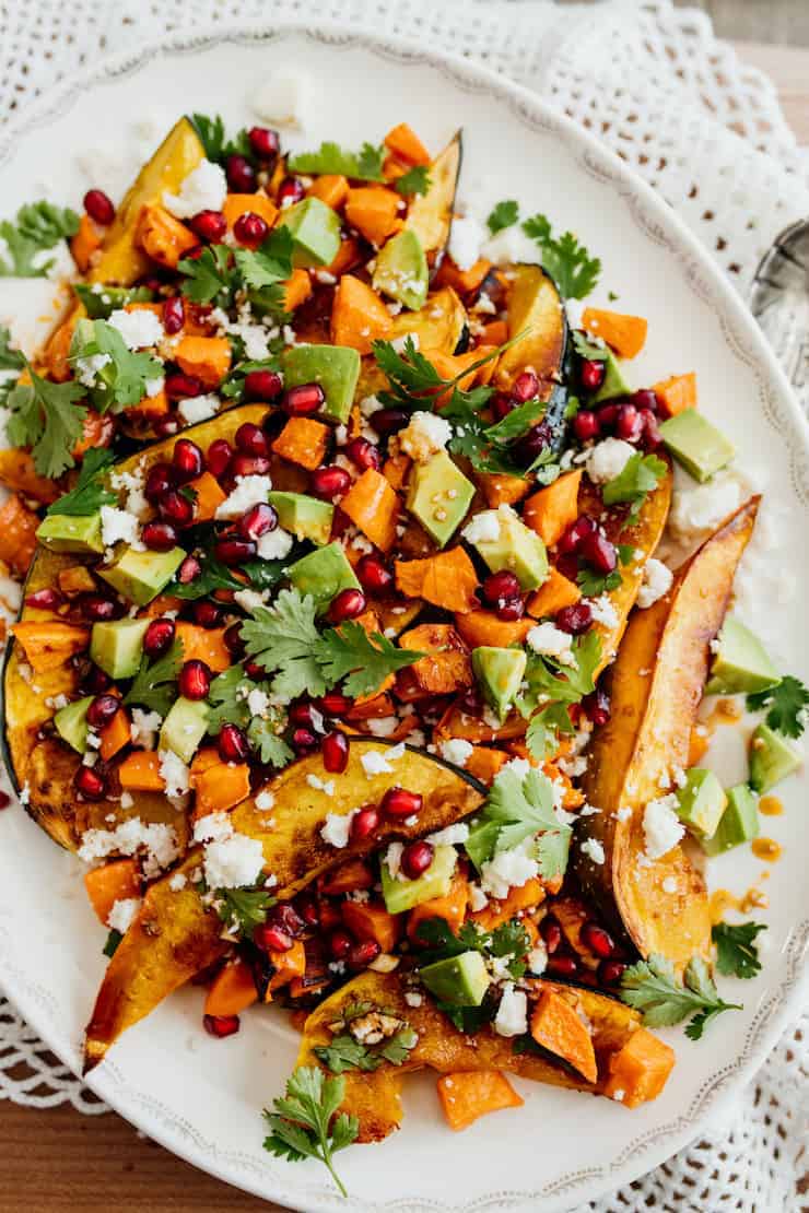 winter roasted salad with sweet potatoes and acorn squash on a white oval platter