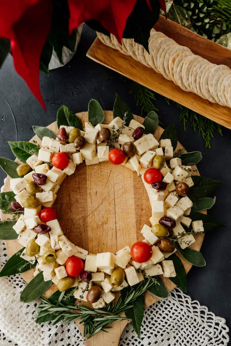christmas wreath cheese board on a round wooden tray with a side of water crackers