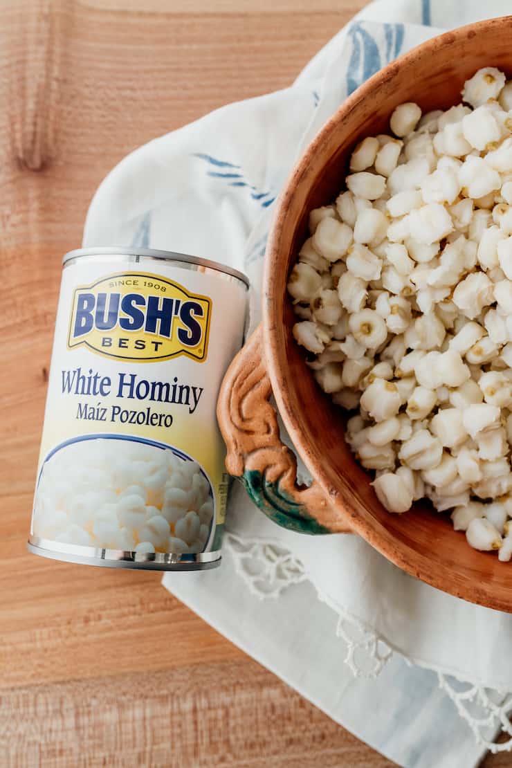 can of bush's white hominy next to an earthenware bowl filled with hominy
