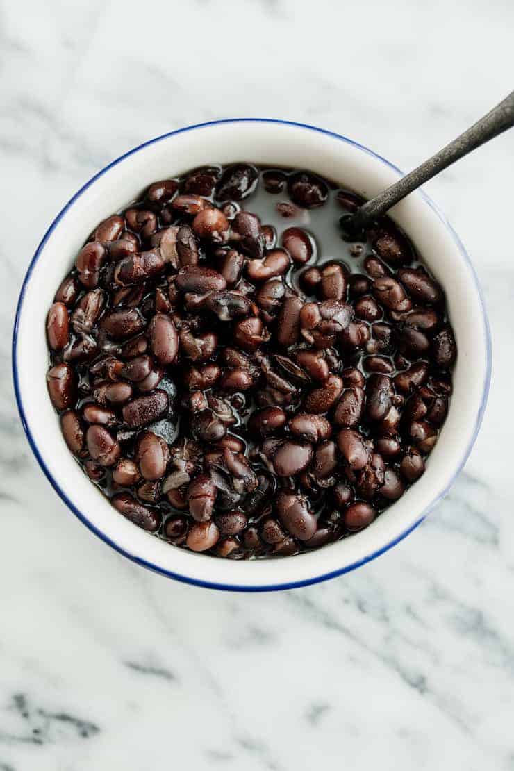 overhead shot of instant pot black beans in a white bowl with a blue rim and a silver fork