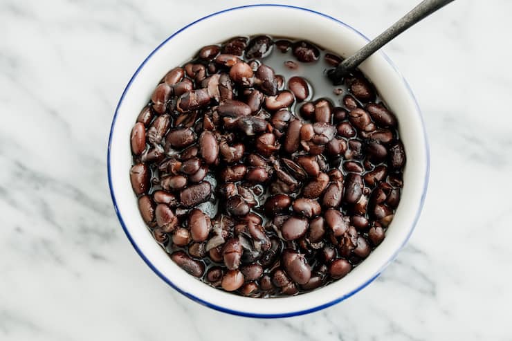 brothy black beans in a white bowl with a blue rim