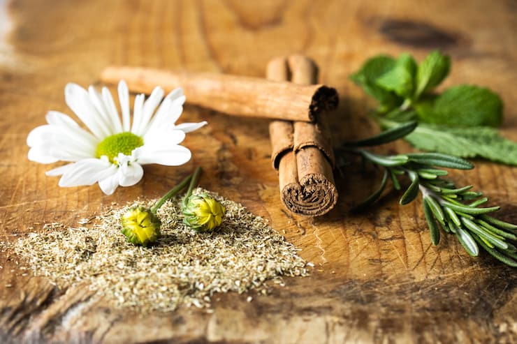 cinnamon sticks, rosemary, chamomile and mint on a wooden board
