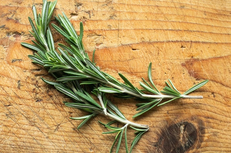 fresh rosemary sprigs on a wooden surface 
