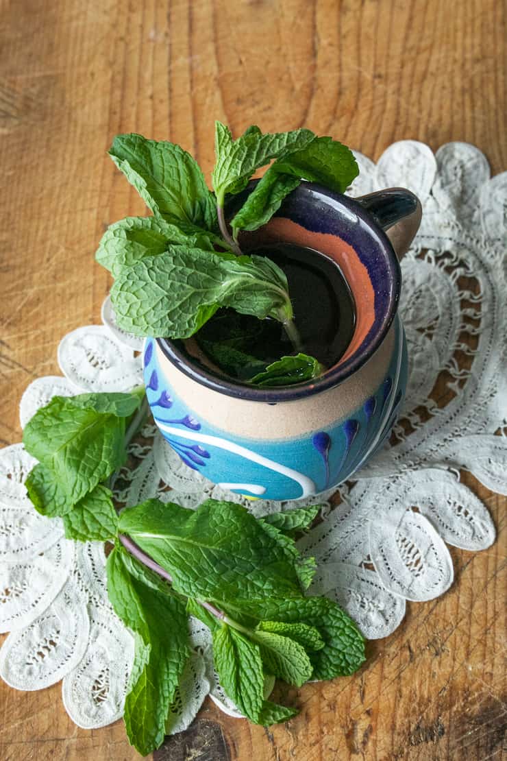 Hierbabuena (Mint Tea) in a Mexican pottery cup on a vintage white doily and wood background